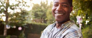 Man standing in front of wooded background smiles at camera