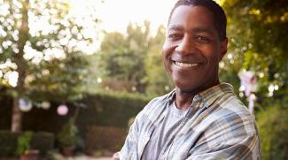 Man standing in front of wooded background smiles at camera