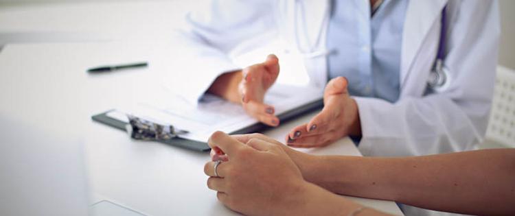 Photo of arms of a doctor and a patient having a discussion.