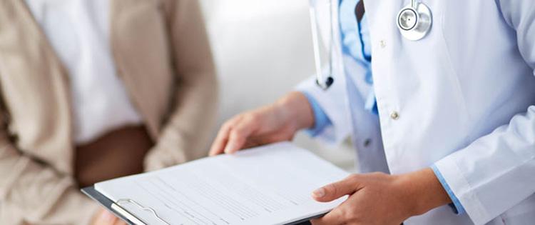 Photo of a doctor and patient's arms with a clipboard between them