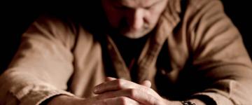 Man sitting with hands folded in front of him