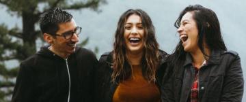 Dos mujeres y un hombre riendo afuera