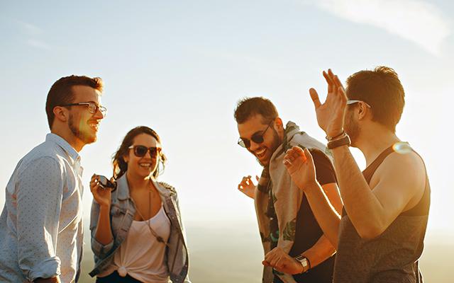 A set of four friends face each other while having fun in an outdoor setting near sunset.  