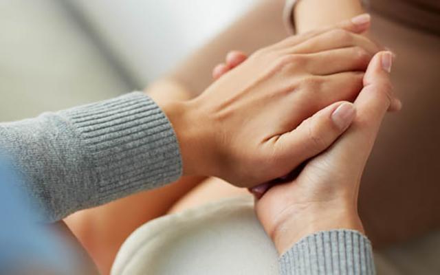 Woman's hands holding another woman's hand