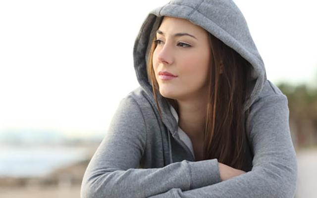 woman in sweatshirt sitting in front of lake 