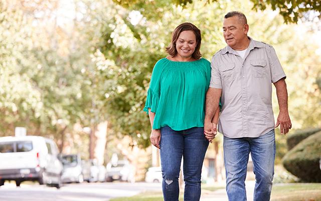 Un hombre y una mujer dando un paseo afuera y cogidos de la mano.