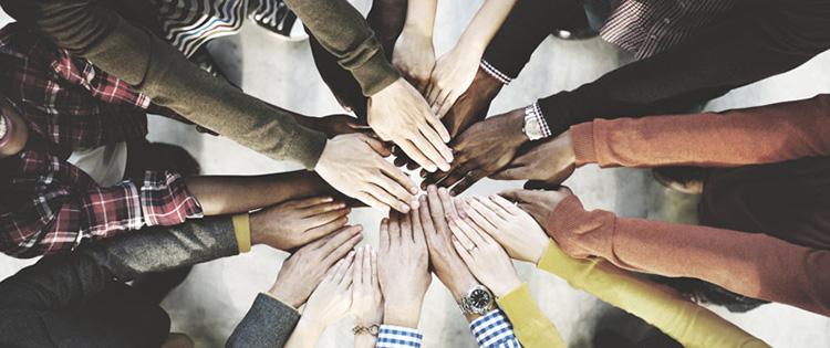 Photo of many people's outstretched arms with hands meeting in the middle